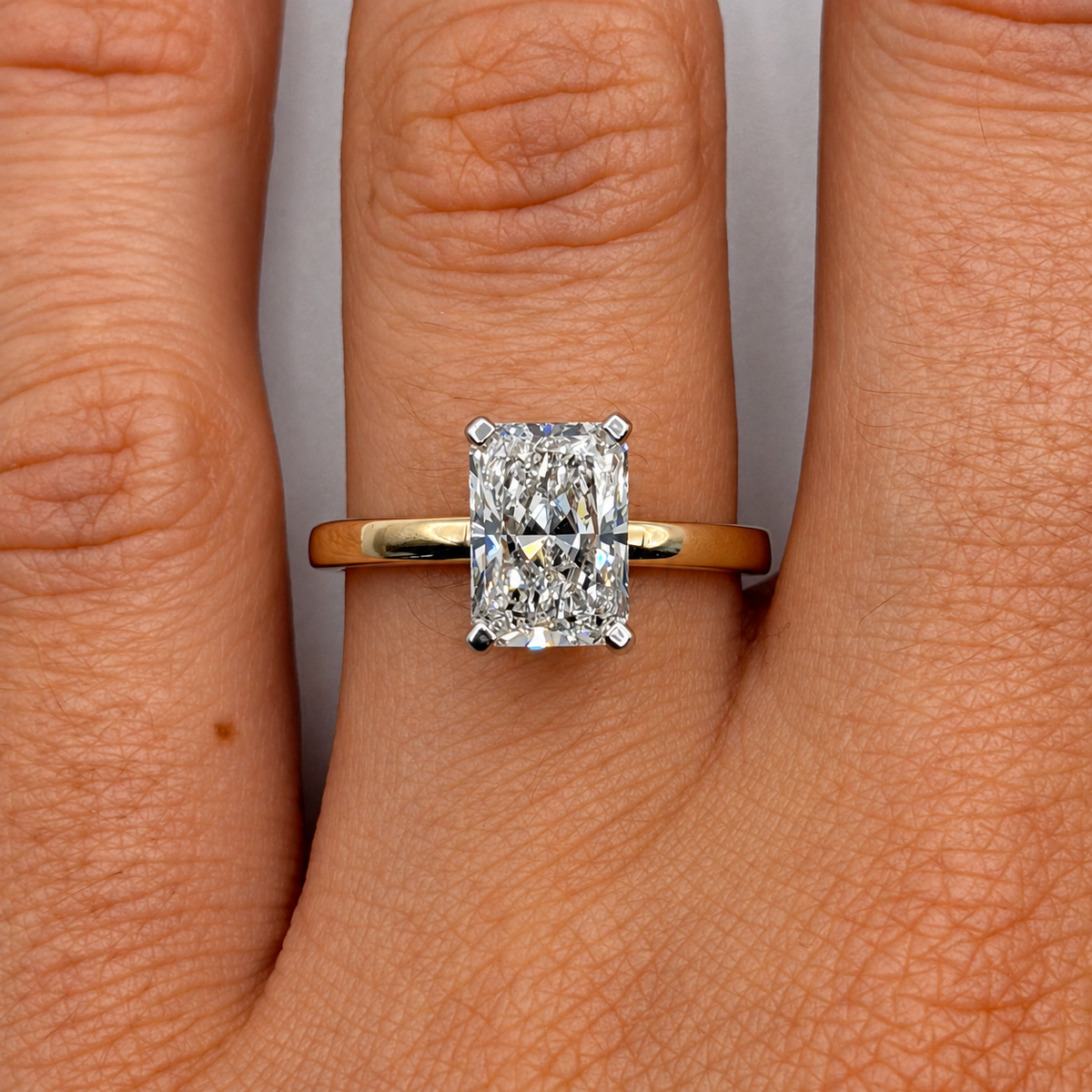 2.04 carat radiant-cut solitaire diamond ring in yellow gold worn on hand